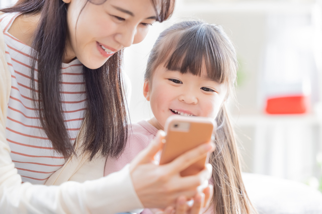 子供と一緒にスマートフォンを操作している女性