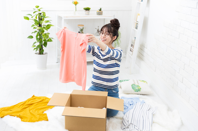 段ボールから衣服を取り出している女性