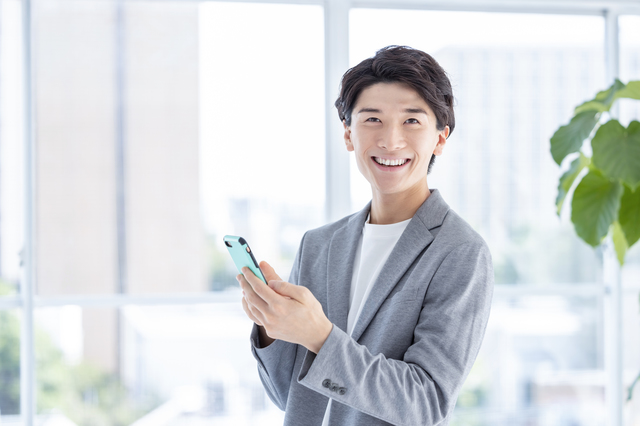 スマホを手にこちらを向いている男性