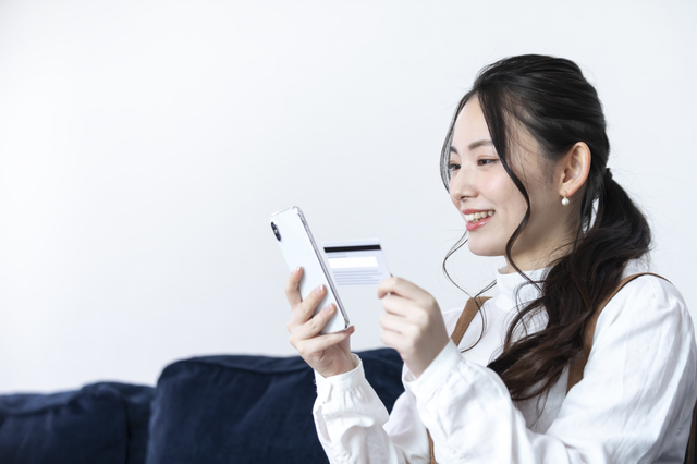 スマホとクレジットカードを手に持つ女性