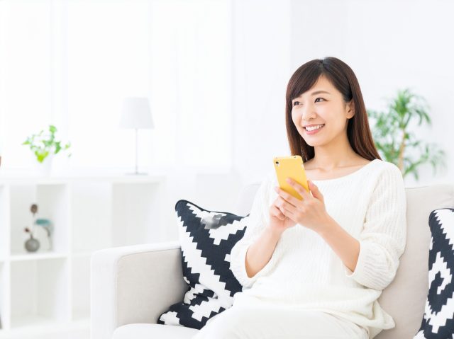 ソファでスマホを操作している女性