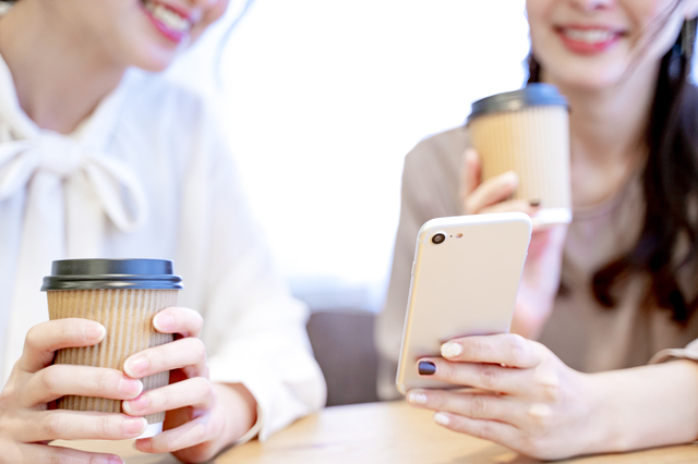 スマホを眺めて会話する女性